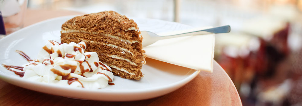 A slice of cake and cream served on a plate with a spoon.