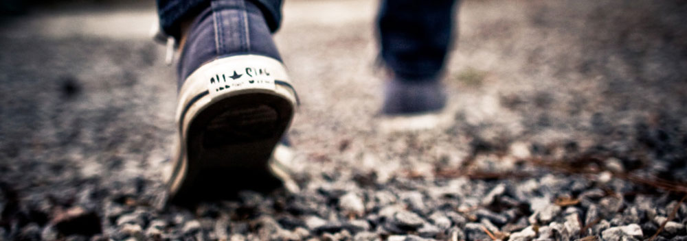 Photo of a person wearing Converse All Star shoes walking away from the camera.